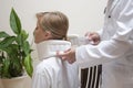 Orthopedic surgeon puts on a white orthopedic collar of a young woman sitting on a chair.