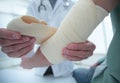 Orthopedist applying bandage onto patient`s hand in clinic Royalty Free Stock Photo