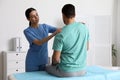 Orthopedist examining man in clinic. Scoliosis treatment