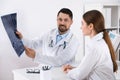 Orthopedists examining X-ray picture at desk in clinic