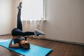 Ortrait of beautiful young woman working out at home in living room, doing yoga or pilates exercise on mat