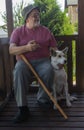 Ortrait of happy mixed breed white young dog with its merry bearded senior master sitting together