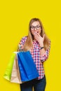 Ortrait of young pretty surprised woman holding shopping bags , isolated on yellow background Royalty Free Stock Photo