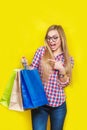 Ortrait of young pretty surprised woman holding shopping bags , isolated on yellow background Royalty Free Stock Photo