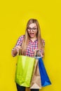 Ortrait of young pretty surprised woman holding shopping bags , isolated on yellow background Royalty Free Stock Photo