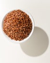 Red Rice seed. Grains in a bowl. Shadow over white table. Royalty Free Stock Photo