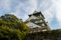 Osaka Castle majestic main tower with green traditional roofs and gold cravings, seen from below, Osaka, Japan.