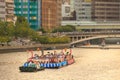Osaka, Japan - July 25, 2023: Tug boat pulls crowded barge down river at Tenjin Matsuri