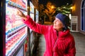 Unidentified senior woman buys a bottle of water from a vending machine