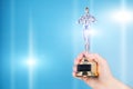 Oscar award, trophy statue in hand on blue background,copy space Royalty Free Stock Photo