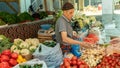 Local vendor selling fresh fruits and vegetables in a stall at Osh market, Kyrgyzstan