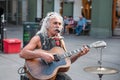 Oslo, Norway-August 1, 2013: a street musician performs on the main street of Karl Johans gate. An elderly man with long white