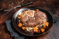 Osso buco cross cut veal shank with mashed potato on a plate. Dark background. Top view