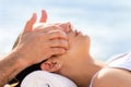 Osteopath doing treatment on female cheek outdoors. Royalty Free Stock Photo