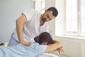 Osteopath in medical uniform fixing woman patients shoulder and back joints in manual therapy clinic