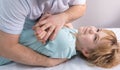 An osteopath works with the child. Work with the chest, shoulders and spine. There is a teenage child on the couch