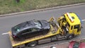 Loading of the black car Skoda Rapid onto yellow Europ Assistance towing truck