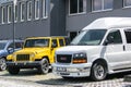 GMC Savana passenger van and Jeep Wrangler SUV in front of dealership in Ostrava