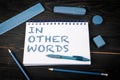 In Other Words. Notepad and blue stationery on a black wooden texture background Royalty Free Stock Photo