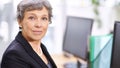 Others in the office look up to her. Portrait of a mature woman sitting in an office. Royalty Free Stock Photo