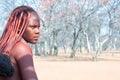 African Himba tribe young woman with traditional hairstyle half-face close up on forest background