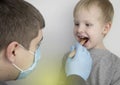 An otolaryngologist examines a child`s throat with a wooden spatula. A possible diagnosis is inflammation of the pharynx, tonsils Royalty Free Stock Photo
