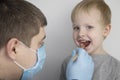 An otolaryngologist examines a child`s throat with a wooden spatula. A possible diagnosis is inflammation of the pharynx, tonsils