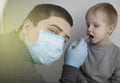 An otolaryngologist examines a child`s throat with a wooden spatula. A possible diagnosis is inflammation of the pharynx, tonsils