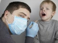 An otolaryngologist examines a child`s throat with a wooden spatula. A possible diagnosis is inflammation of the pharynx, tonsils