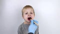 An otolaryngologist examines a child's throat with a wooden spatula. A possible diagnosis is inflammation of the pharynx, tonsils