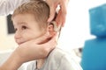 Otolaryngologist putting hearing aid in little boy's ear indoors Royalty Free Stock Photo