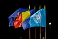 NATO, Romania, European Union and United Nations flags in the wind at night