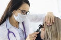 Otorhinolaryngologist looking at female patients ear with otoscope in clinic