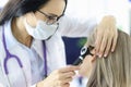 Otorhinolaryngologist looking at patients ear with otoscope in clinic