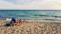 People relaxing at the sea with turquoise water and golden beach at sunset in Alimini, Salento,Puglia, Italy