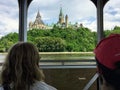 Tourists taking in the views of Parliament Hill and the cityscape while taking a tour boat across the Ottawa River