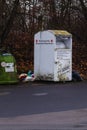 OTTBERGEN, GERMANY - Dec 20, 2020: Old clothes container of the german red cross with plastic bags laying around it Royalty Free Stock Photo