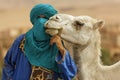 Berber dressed his traditional clothes and turban and keeps the camels bit