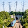 A Ouigo TGV Duplex high-speed train is entering a tunnel under a row of transmission towers Royalty Free Stock Photo