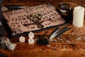 Ouija Board with candles. Seance on wooden table. The mystical atmosphere of the call of spirits. Black magic