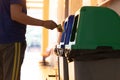 Oung Asian men dump cans or plastic bottles in sorting bins for recycling