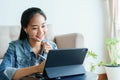 Oung Asian women is conducting video conference with her co-worker using tablet computer via technology at home. beautiful woman Royalty Free Stock Photo