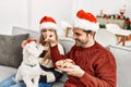 oung hispanic couple wearing christmas hat drinking coffee and eating cookies