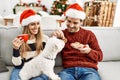 oung hispanic couple wearing christmas hat drinking coffee and eating cookies Royalty Free Stock Photo