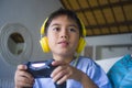 Oung hispanic little kid excited and happy playing video game online with headphones holding controller enjoying having fun sittin