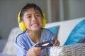 Oung hispanic little kid excited and happy playing video game online with headphones holding controller enjoying having fun sittin