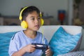 Oung hispanic little kid excited and happy playing video game online with headphones holding controller enjoying having fun sittin