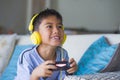 Oung hispanic little kid excited and happy playing video game online with headphones holding controller enjoying having fun sittin