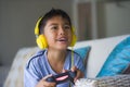 Oung hispanic little kid excited and happy playing video game online with headphones holding controller enjoying having fun sittin