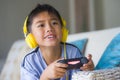 Oung hispanic little kid excited and happy playing video game online with headphones holding controller enjoying having fun sittin